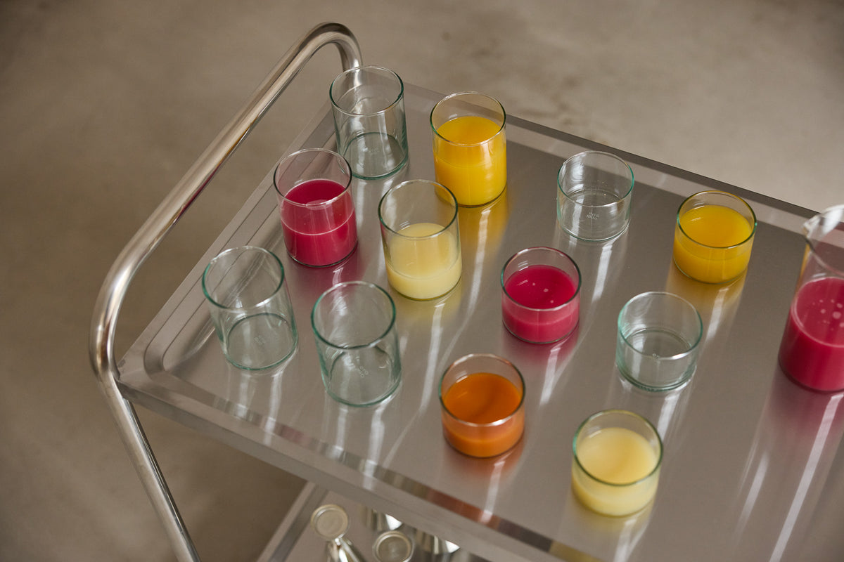 Mundgeblasene Trinkgläser mit Saft und Wasser auf einem verchromten Servierwagen