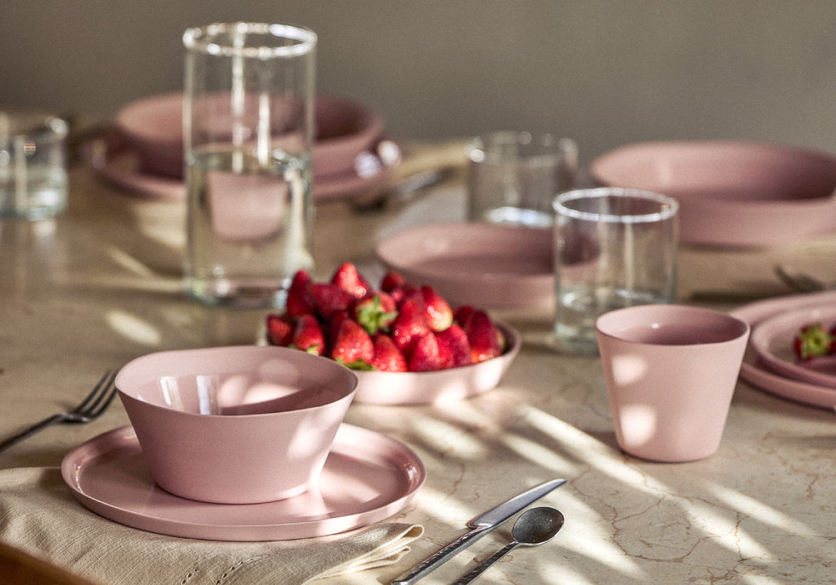 Gedeckter Frühstückstisch mit rosa Geschirr, Erdbeeren und Wassergläsern